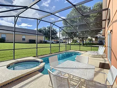 a patio with a table and chairs and a swimming pool at Emerald Island Resort 4 bed 3 bath with pool/spa in Kissimmee
