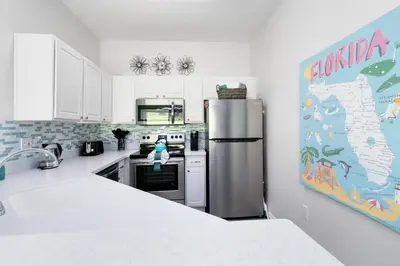 a kitchen with a refrigerator and a map on the wall at Disney Area 4 bed/ 3.5 Bathroom Emerald Island in Kissimmee