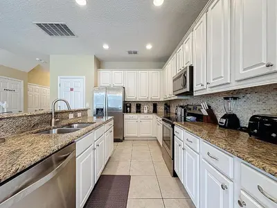 a kitchen with white cabinets and a stainless steel refrigerator at Veranda Home, 8br, 6 en-suites, Lake View,POOL/SPA in Kissimmee