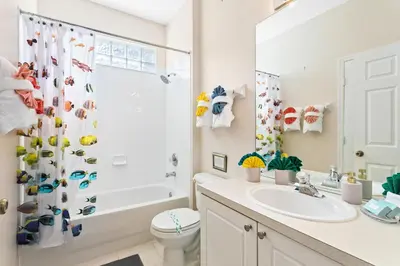 a white bathroom with a shower and a sink at South Facing Pool 4 Bedroom 3 Bath Villa in Kissimmee
