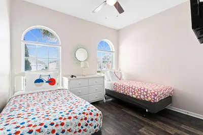 a bedroom with two beds and a dresser and two windows at South Facing Pool 4 Bedroom 3 Bath Villa in Kissimmee