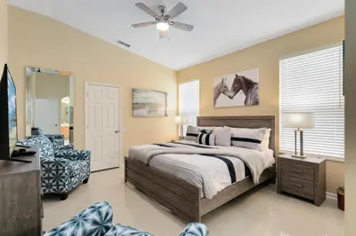 a bedroom with a bed and a chair and a fan at Amazing Disney Dream Getaway in Windsor Palms! in Kissimmee