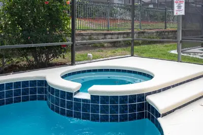 a swimming pool with a tiled floor and a fence at Amazing Disney Dream Getaway in Windsor Palms! in Kissimmee