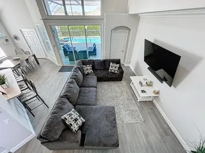 a living room with a couch and a flat screen tv at Amazing 6 Bed Disney Dream Getaway in Windsor Palm in Kissimmee
