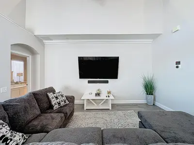 a living room with a couch and a tv on a wall at Amazing 6 Bed Disney Dream Getaway in Windsor Palm in Kissimmee