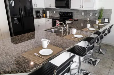 a kitchen with a sink and a counter with stools at Amazing 4 bedroom house near Disney in Kissimmee