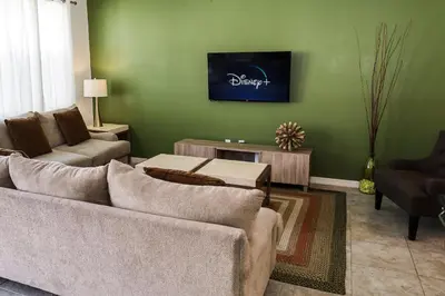 a living room with a couch and a tv on a green wall at Amazing 4 bedroom house near Disney in Kissimmee