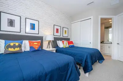a bedroom with two beds with batman pillows at 5 Min to Disney Dream 5 Suites Villa in Orlando
