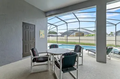 a patio with a table and chairs and a pool at 3Br 2Ba Private Pool Villa just steps away from villa in Kissimmee