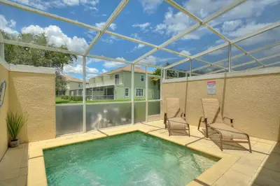 a swimming pool with two chairs and a house at Priceless Peace At Serenity By Shine Villas 081 in Orlando
