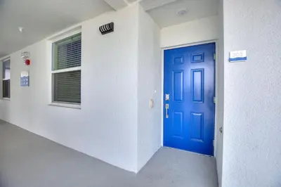 an empty hallway with a blue door and a window at Resort Life At Storey Lake By Shine Villas #702 in Kissimmee