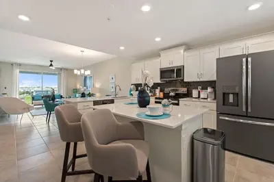 a kitchen with white cabinets and a kitchen island with chairs at Resort Life At Storey Lake By Shine Villas #702 in Kissimmee