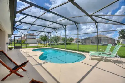 a swimming pool under a glass roof with two chairs and a patio at Gilded Parasol By Shine Villas Remington Golf 420 in Kissimmee