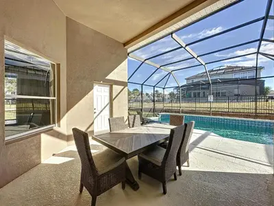 a dining room with a table and chairs and a pool at Luxury 6BD 3.5BA Pool Home in Windsor Palms Resort in Kissimmee