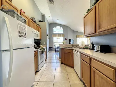 a kitchen with a white refrigerator and wooden cabinets at Emerald Island 4 bed mins to Disney in Kissimmee
