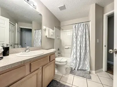 a bathroom with a sink and a toilet and a shower at Four Bed Three Bath in a gated community with pool in Kissimmee