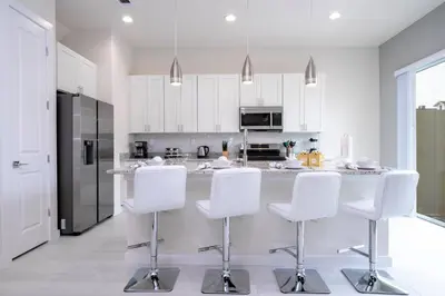 a kitchen with white cabinets and white bar stools at 5 min to Disney NEW Upscale 5 Suites Villa in Orlando
