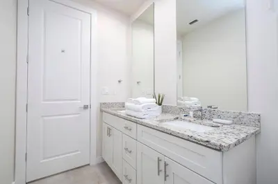 a white bathroom with a sink and a mirror at 5 min to Disney NEW Upscale 5 Suites Villa in Orlando