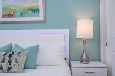 a bedroom with a bed with a lamp on a night stand at 5 min to Disney NEW Upscale 5 Suites Villa in Orlando