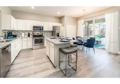 a kitchen with white cabinets and a table with chairs at The Minions Mansion 6br Resort Pool Home By Disney in Kissimmee