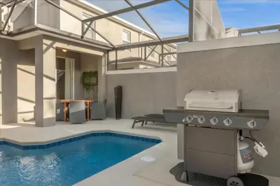 a backyard with a grill and a swimming pool at 5 Bedrooms 4 Bathrooms Storey Lake 2533 Rt in Kissimmee