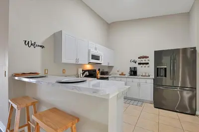 a kitchen with white cabinets and a stainless steel refrigerator at Remodeled Retreat: Tranquil Resort Oasis Near Theme Parks in Kissimmee