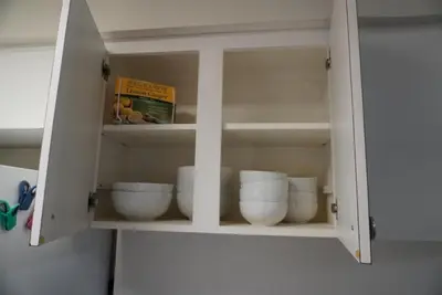 a cabinet filled with white bowls and a book at House of Blues-3 Bedrooms+GameRoom in Orlando