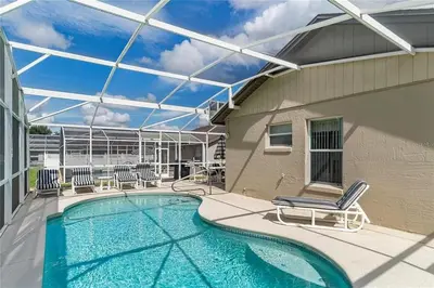 a swimming pool with lounge chairs and a building at 1589-IBRHAIM · Charming new 4bd in the heart of Kissimmee 1589 in Orlando