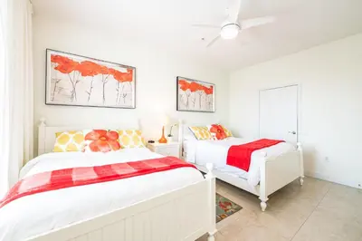 a white bedroom with two beds and a ceiling fan at Top Floor*Balcony*VistaCay Convention Ctr & Idrive in Orlando
