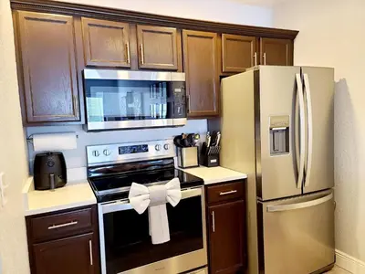 a kitchen with wooden cabinets and a refrigerator with a bow at Your home 5 * near Disney in Kissimmee