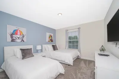two beds in a room with a tv at 5013MO TOWNHOUSE 4 BEDROOMS & 3 BATHROOMS + POOL in Kissimmee