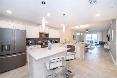 a large kitchen with white cabinets and a large island at 3121-304FR STOREY LAKE, CONDO 2/2 LAKE VIEW in Kissimmee