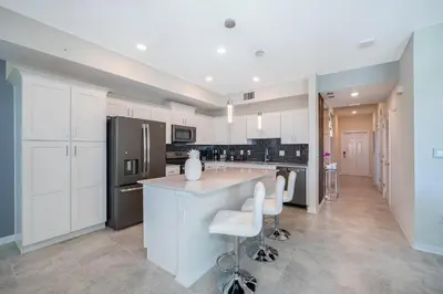 a kitchen with white cabinets and a island with bar stools at 3131-102JJ STOREY LAKE, CONDO 2/2 LAKE VIEW in Kissimmee