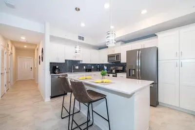 a kitchen with white cabinets and a large island with bar stools at 3141-307DM STOREY LAKE, CONDO 2/2 LAKE VIEW in Kissimmee