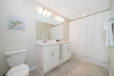 a bathroom with a toilet and a sink and a mirror at 3141-204LS STOREY LAKE, CONDO 2/2 LAKE VIEW in Kissimmee