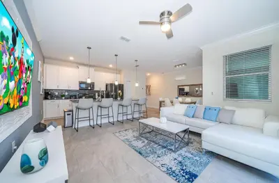 a living room with a white couch and a kitchen at 2921DH TOWNHOUSE 4 BEDROOMS & 3 BATHROOMS + POOL in Kissimmee