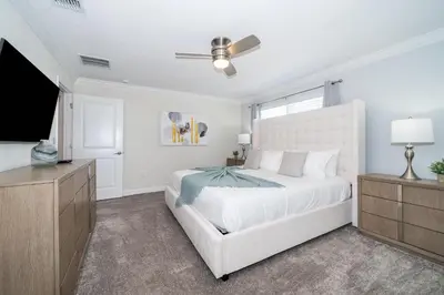 a bedroom with a white bed and a flat screen tv at 2921DH TOWNHOUSE 4 BEDROOMS & 3 BATHROOMS + POOL in Kissimmee