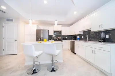 a large white kitchen with white cabinets and white bar stools at 3161-308AB STOREY LAKE, CONDO 3/2 LAKE VIEW in Kissimmee
