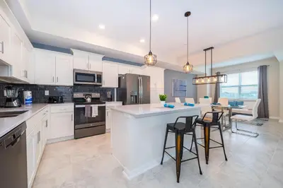 a kitchen with white cabinets and a island with bar stools at 3151-207NC STOREY LAKE, CONDO 2/2 LAKE VIEW in Kissimmee