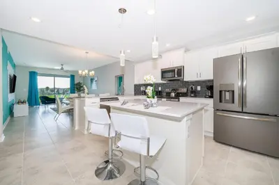 a kitchen with white cabinets and a large island with bar chairs at 3161-205RF STOREY LAKE, CONDO 2/2 LAKE VIEW in Kissimmee