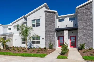 a white house with red doors at 4381FA TOWNHOUSE 4 BEDROOMS & 3 BATHROOMS + POOL in Kissimmee
