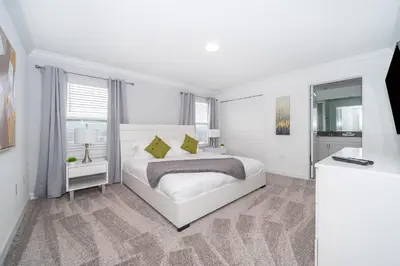 a white bedroom with a white bed and a window at 2984JP TOWNHOUSE 4 BEDROOMS & 3 BATHROOMS + POOL in Kissimmee
