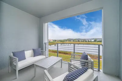 a balcony with a couch and chairs and a large window at 3171-204AZ STOREY LAKE, CONDO 2/2 LAKE VIEW in Kissimmee