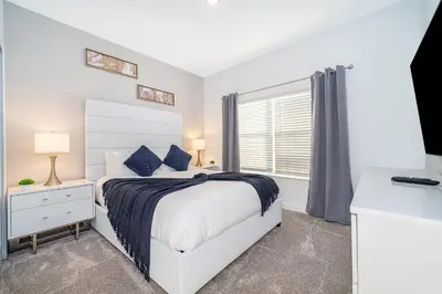 a white bedroom with a bed and a window at 3005PB TOWNHOUSE 5 BEDROOMS & 4 BATHROOMS + POOL in Kissimmee