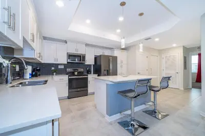a kitchen with white cabinets and a island with bar stools at 4721-201AB STOREY LAKE, CONDO 3/2 GARDEN VIEW in Kissimmee