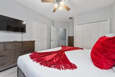 a bedroom with a bed with a red blanket on it at Epic Location 3BR Home w Full Comfort in Orlando