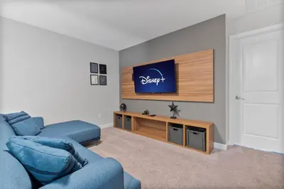 a living room with a blue couch and a flat screen tv at Luxury Villa 5BedroomsPool- 4 miles from Disney in Orlando