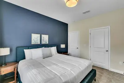 a bedroom with a large bed and a blue wall at Stylish Family Home - Private Pool - STL111 in Kissimmee
