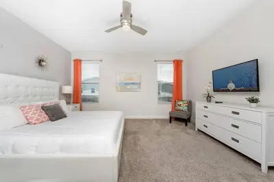a bedroom with a white bed and a tv at Relax & Unwind Chic Pool Home Near Disney Fun! - STL113 in Kissimmee