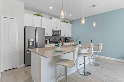 a kitchen with a large island with chairs and a refrigerator at Lovely Family Home - 8 Min to Disney! - STL106 in Kissimmee
